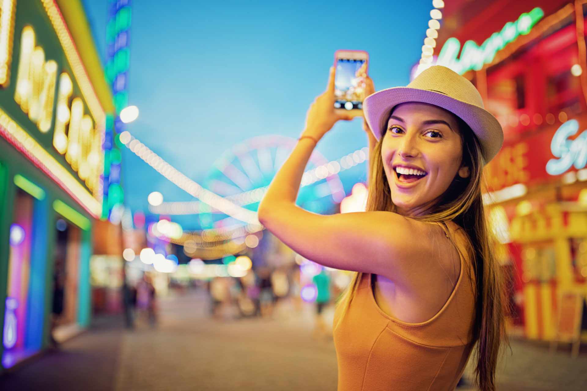 Glückliches Mädchen mit einem Smartphone auf der Kirmes